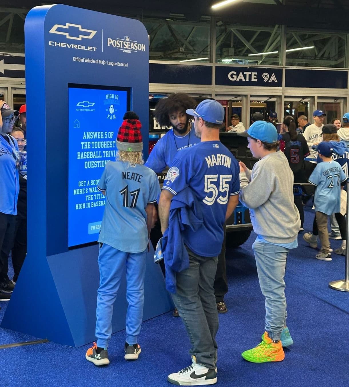 Fans interacting with a BIG Digital touchscreen kiosk during a Chevrolet-sponsored contest, demonstrating interactive sponsor activation at a live sports venue.