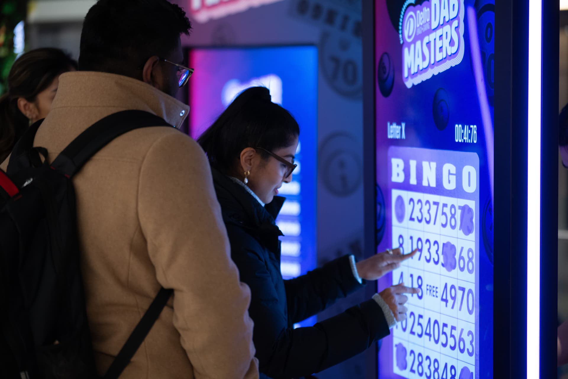 Guests playing an interactive bingo game on a BIG Digital touchscreen kiosk at a live event, demonstrating audience engagement technology.